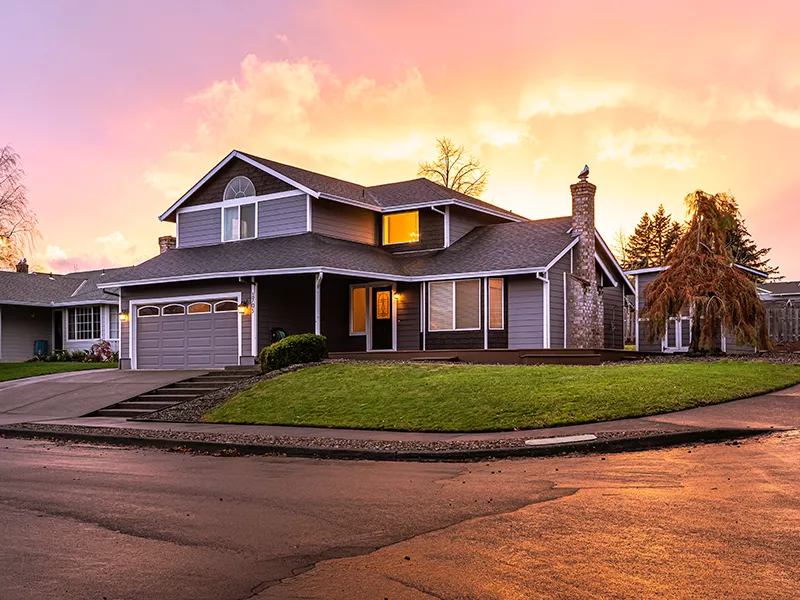 The sun sets behind a home.