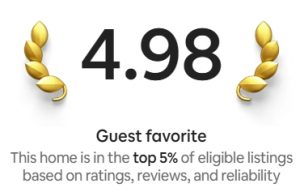a screenshot of Airbnb's Guest Favorite Badge in the top 5%, with gold emblem around the numbers 4.98. The words "Guest Favorite" sit above the text "This home is in the top 5% of eligible listings based on ratings, reviews, and reliability"